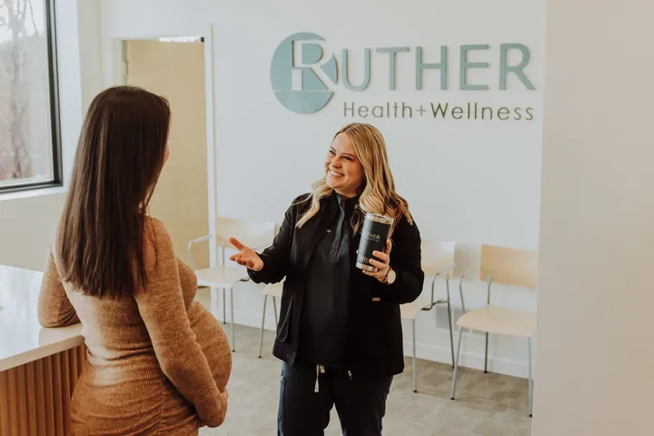 A therapist welcoming a pregnant patient in the clinic lobby