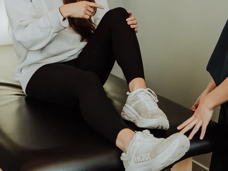 A therapist assessing a patient's lower leg and foot on the treatment table
