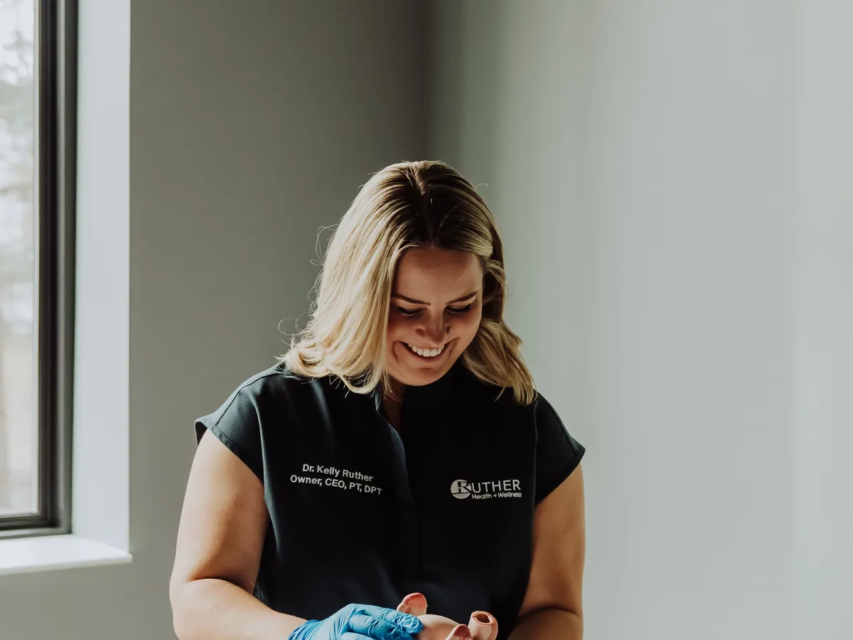 A Ruther Health + Wellness therapist in gloves preparing treatment for a patient on the table