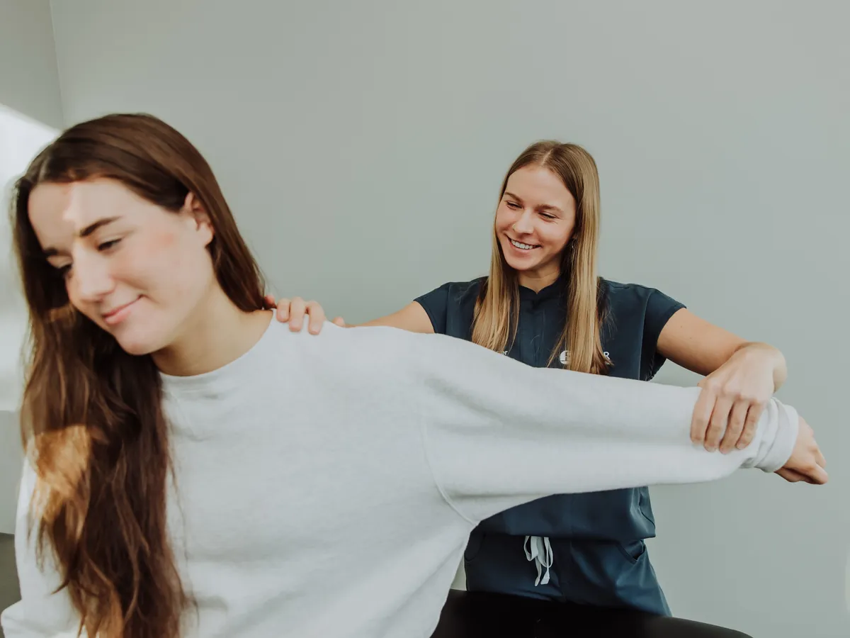 A therapist guiding a patient's arm and shoulder through a stretch