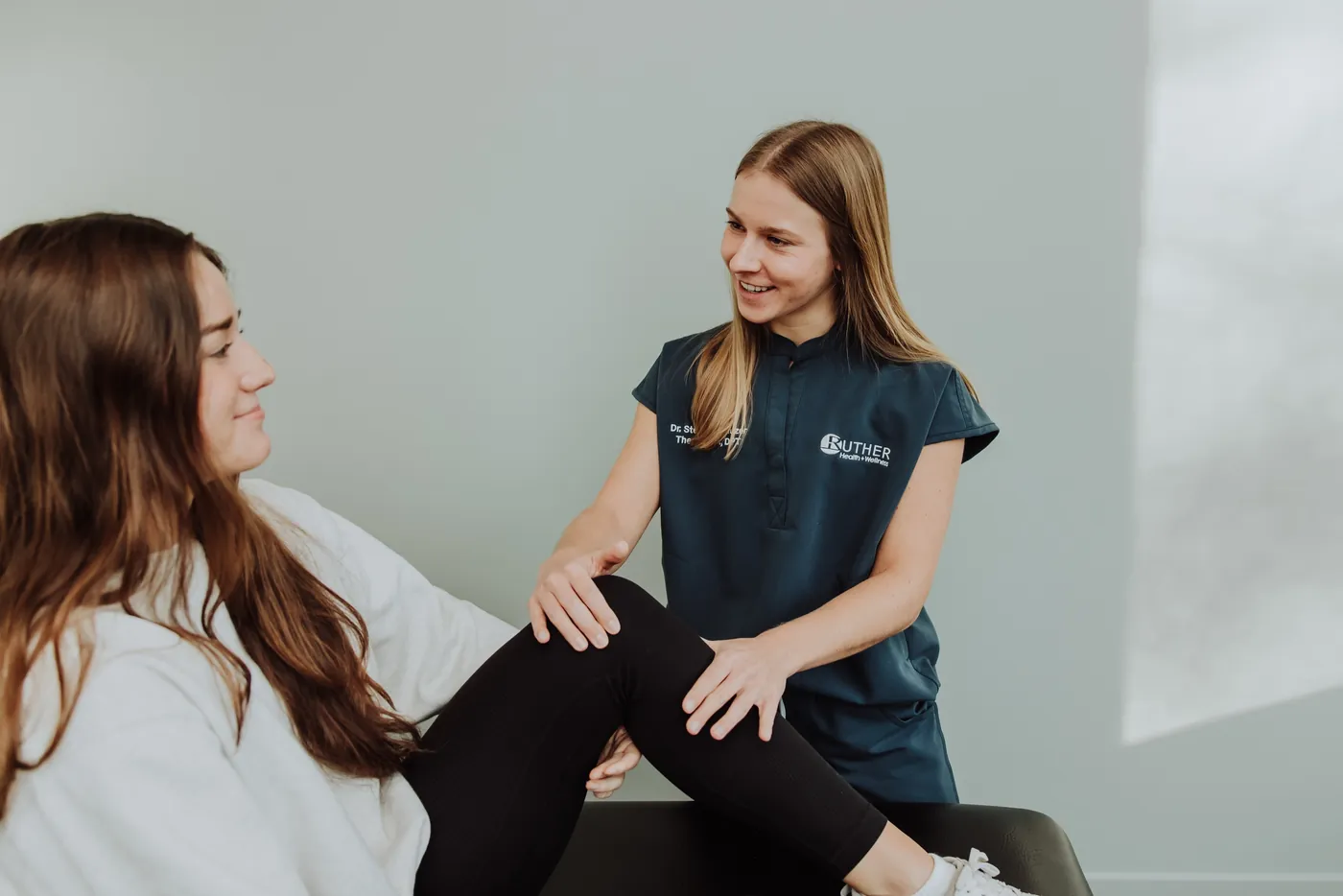 A Ruther Health + Wellness physical therapist assessing a patient's knee and hip
